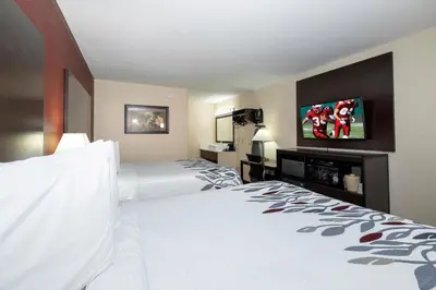 a hotel room with a bed and a flat screen tv at Red Roof Inn Freehold in Freehold
