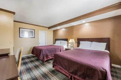 a hotel room with two beds and a table at Knights Inn Trevose in Trevose
