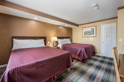 a hotel room with two beds with purple sheets at Knights Inn Trevose in Trevose