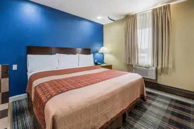 a large bed in a room with a blue wall at Knights Inn Trevose in Trevose