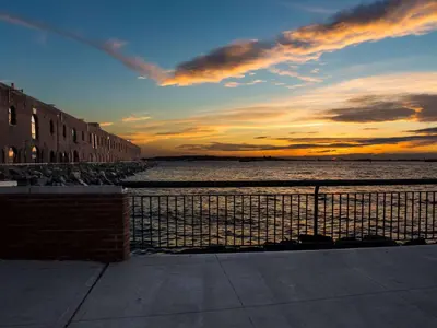 a sunset over a body of water with a fence at The Lodge Red Hook in Brooklyn