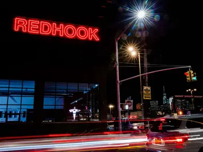 a red shoot neon sign on a building at night at The Lodge Red Hook in Brooklyn