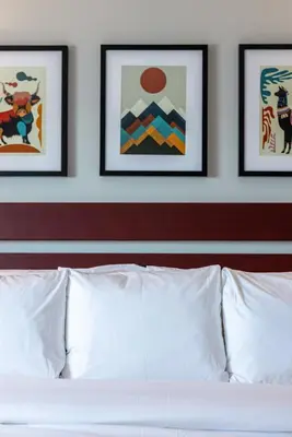a white bed with three framed pictures on a wall at The Lodge Red Hook in Brooklyn