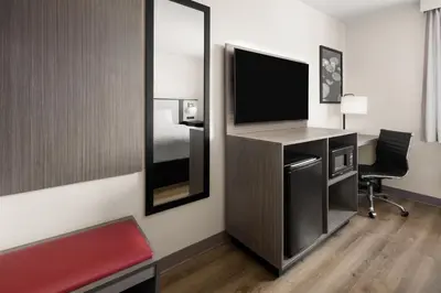 a room with a desk with a tv and a mirror at Ramada by Wyndham York Harrisburg Hershey in York