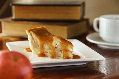 a piece of cake on a plate on a table with an apple at Sheraton Great Valley Hotel in Frazer