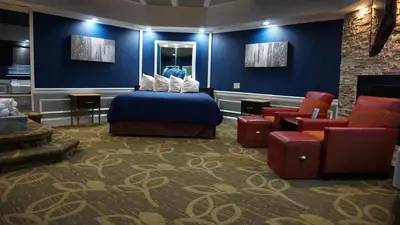 a hotel room with a bed and a couch and chairs at Inn of the Dove Cherry Hill - Philadelphia in Cherry Hill