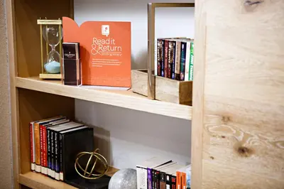 a book shelf with books and a box on it at Country Inn & Suites by Radisson, Harrisburg West Mechanicsburg in Mechanicsburg