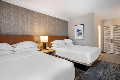 a hotel room with two beds and a lamp at Sheraton Suites Wilmington Downtown in Wilmington