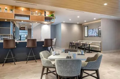 a dining room with tables and chairs and a bar at Sheraton Suites Wilmington Downtown in Wilmington