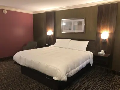 a large white bed in a hotel room with two lights at The Lincoln Hotel Philadelphia in Trevose