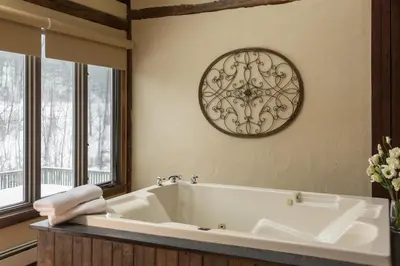a bathroom with a tub and a clock on the wall at Glasbern in Fogelsville