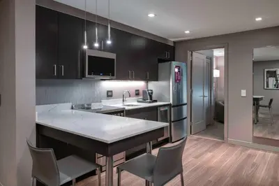 a kitchen with black cabinets and a kitchen island with chairs at Residence Inn by Marriott Weehawken in Weehawken