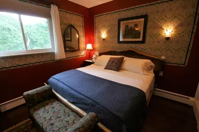 a bedroom with a bed and a chair and a window at Alpenhof Bed & Breakfast in Media