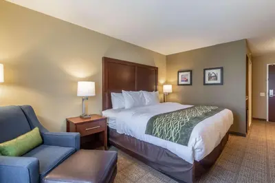 a hotel room with a bed and a chair at Comfort Inn & Suites - Harrisburg Airport - Hershey South in Middletown