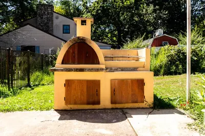 a dog house with two wooden doors in a yard at Red brick house in Chalfont