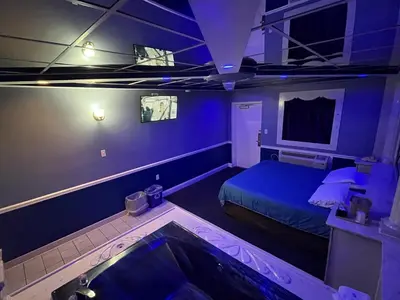 a blue room with a bed and a tub at Gallery Holiday Motel in South Amboy