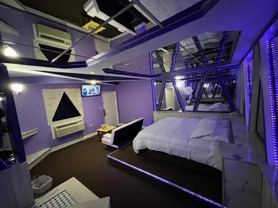 a bedroom with purple walls and a bed and a couch at Gallery Holiday Motel in South Amboy
