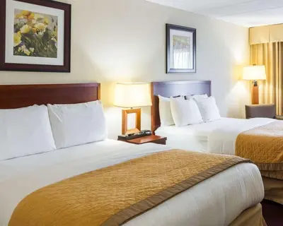 two beds in a hotel room with two lamps at Clarion Hotel Somerset - New Brunswick in Somerset