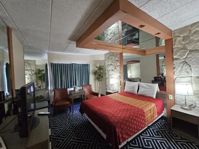 a hotel room with a red bed and a tv at La Mirage Motor Inn in Monmouth Junction