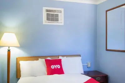 a blue room with a bed with a red pillow at OYO Hotel Wilkes-Barre East in Wilkes-Barre