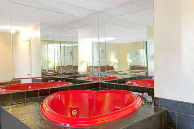 a large red tub in a bathroom with many mirrors at Knights Inn South Hackensasck in South Hackensack