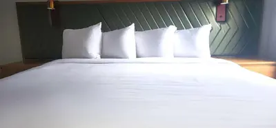 a large bed with white sheets and pillows at Penn Lodge Hotel & Suites Philadelphia - Bensalem in Bensalem