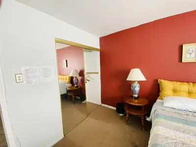 a hotel room with a bed and a red wall at Airport Xpress Guestrooms in Philadelphia