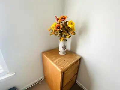 a vase of flowers sitting on top of a wooden table at Airport Xpress Guestrooms in Philadelphia