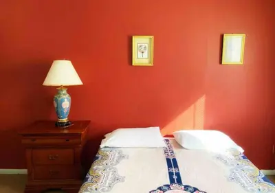 a bedroom with a red wall with a bed and a lamp at Airport Xpress Guestrooms in Philadelphia