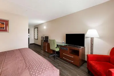 a hotel room with a bed and a desk with a television at Fairmount Inn & Suites - Stroudsburg, Poconos in Delaware Water Gap