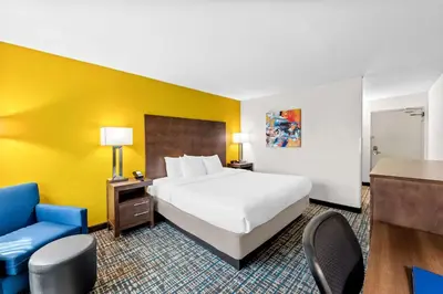 a hotel room with a bed and a blue chair at Best Western Inn at Ramsey in Ramsey