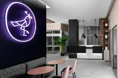a room with two tables and a purple sign on a wall at voco Times Square South New York by IHG in New York