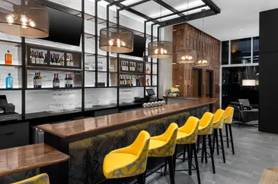 a bar with yellow chairs at a restaurant at voco Times Square South New York by IHG in New York