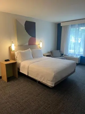 a hotel room with a large bed and a chair at Spark By Hilton Hummelstown Hershey in Hummelstown