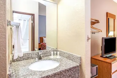 a bathroom with a sink with a mirror and a tv at Super 8 by Wyndham Mahwah in Mahwah