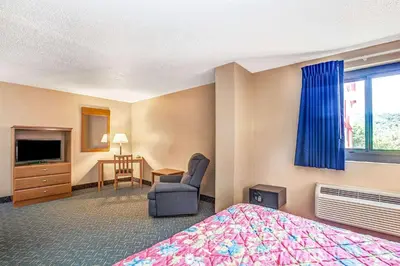 a hotel room with a bed and a chair and a desk at Super 8 by Wyndham Mahwah in Mahwah