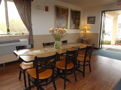 a dining room table with chairs and a vase of flowers at Super 8 by Wyndham Sidney NY in Sidney