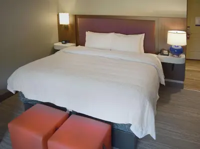 a large bed in a hotel room with a red stool at Hampton Inn & Suites Philadelphia/Media in Media