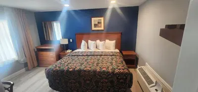 a hotel room with a bed and a blue wall at Budget Inn Horseheads in Horseheads