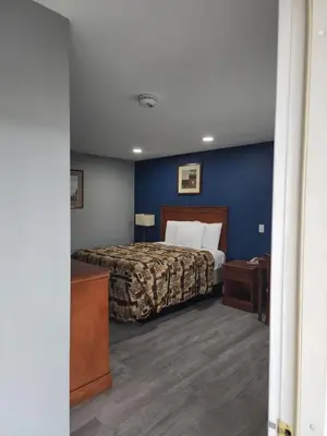 a bedroom with a bed and a blue wall at Budget Inn Horseheads in Horseheads