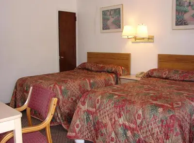 a hotel room with two beds and a table at Red Carpet Inn & Suites Morgantown in Morgantown