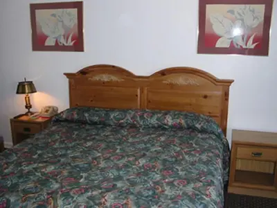 a bedroom with a bed with a wooden head board at Red Carpet Inn & Suites Morgantown in Morgantown