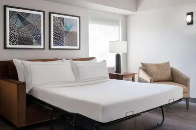a bedroom with a large white bed and a chair at The Alloy, a DoubleTree by Hilton - Valley Forge in King of Prussia