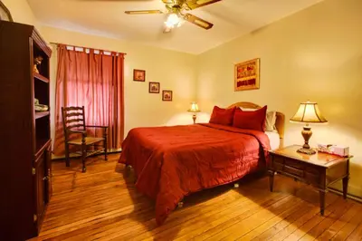 a bedroom with a bed with a red blanket and a table at Suites on Main in Margaretville