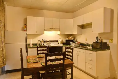 a kitchen with white cabinets and a table with chairs at Suites on Main in Margaretville