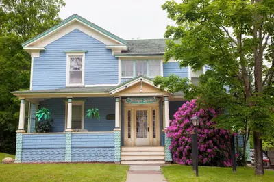 a blue house with pink flowers in front of it at Village Suites in Margaretville