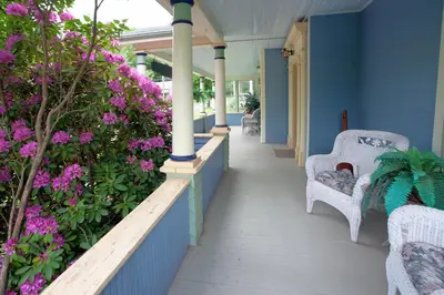 a porch with purple flowers and chairs on a house at Village Suites in Margaretville