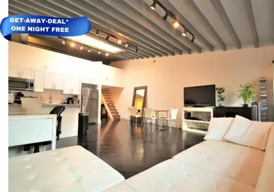 a living room with a white couch and a kitchen at The Havana Lofts in Philadelphia