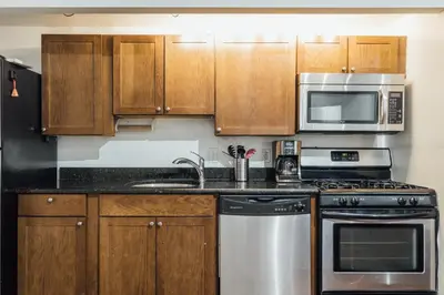 a kitchen with wooden cabinets and stainless steel appliances at The Havana Lofts in Philadelphia
