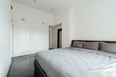 a bedroom with a large bed and a white wall at The Havana Lofts in Philadelphia